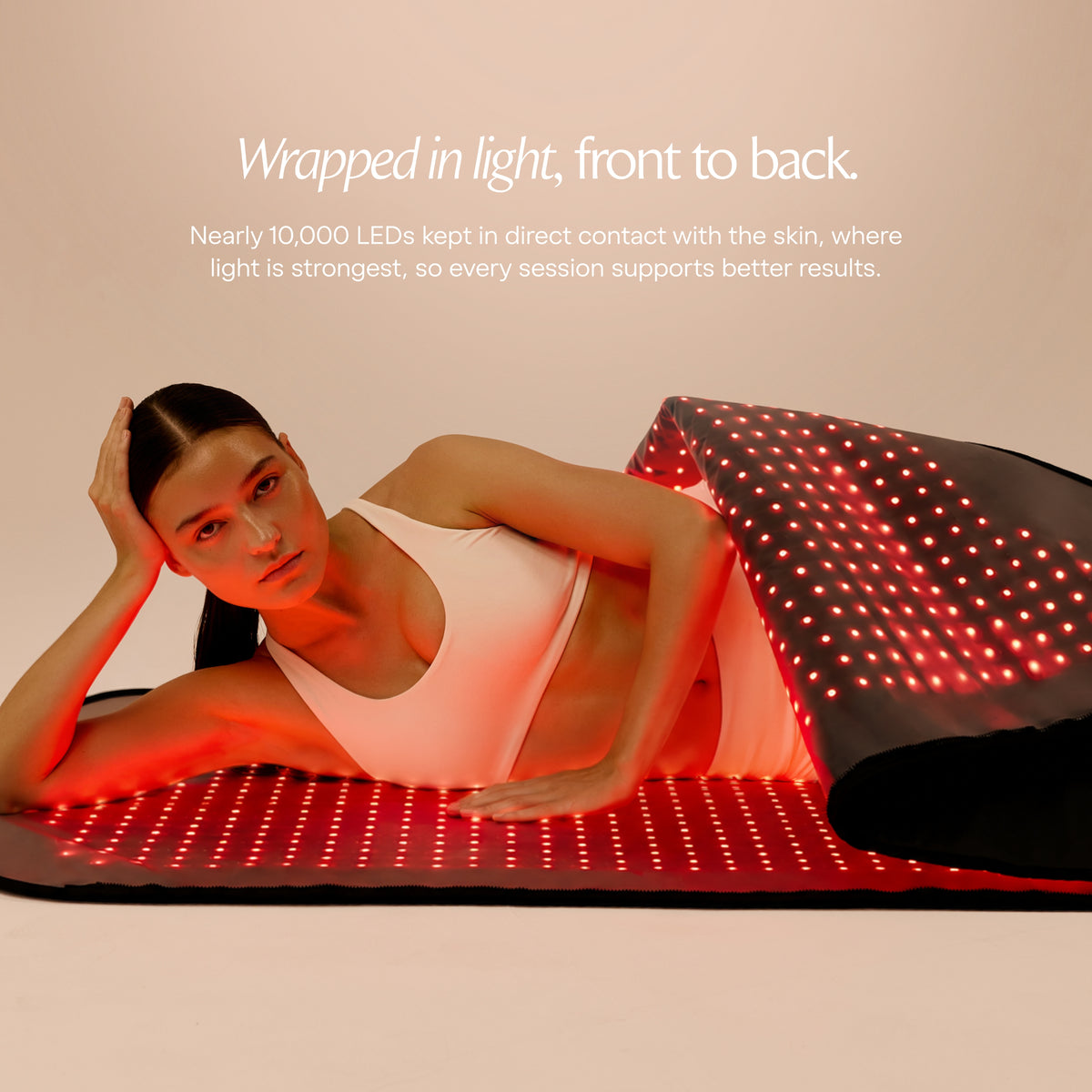Vrouw ligt tussen de verlichte bovenste en onderste panelen van de Restora+ lichttherapiepod